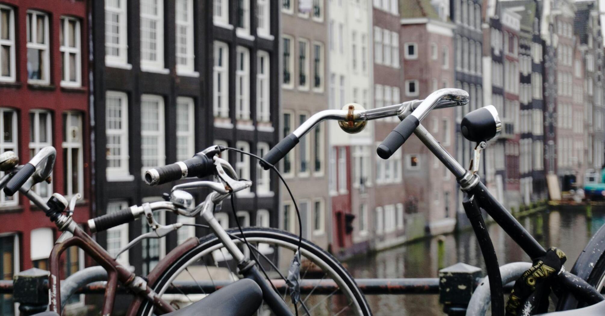 Bicycles parked on a bridge in Amsterdam with traditional canal houses in the background