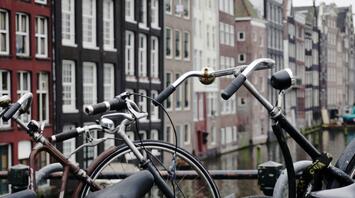 Bicycles parked on a bridge in Amsterdam with traditional canal houses in the background