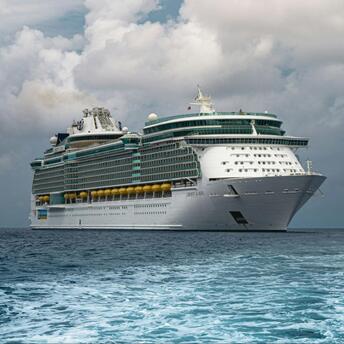 A Royal Caribbean cruise ship sailing in open waters under a cloudy sky