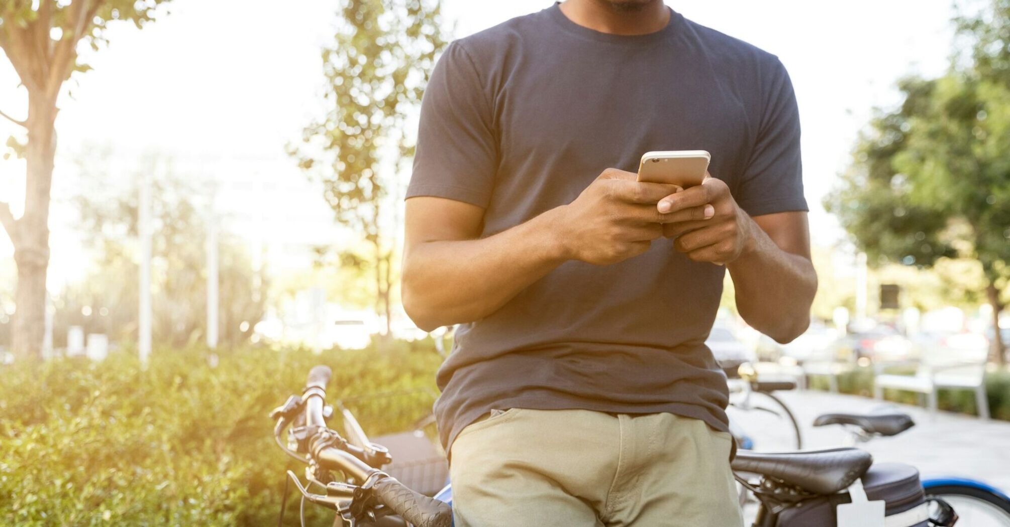 A person using a smartphone outdoors with bicycles nearby