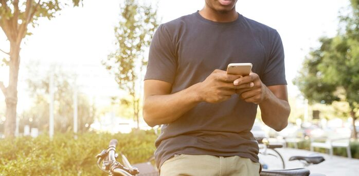 A person using a smartphone outdoors with bicycles nearby