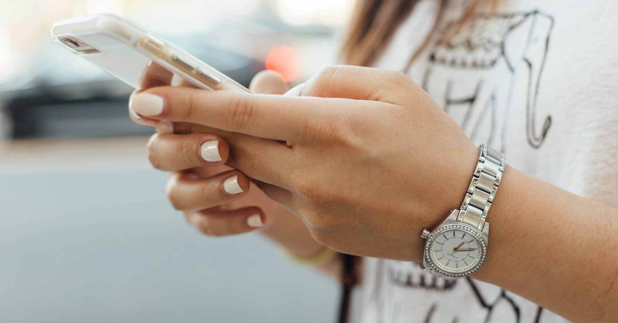 Person holding a smartphone with a silver watch on wrist