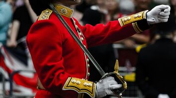 A soldier in a traditional red uniform holds a ceremonial sword during a British royal event