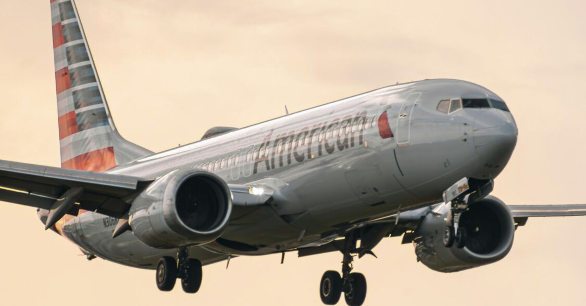 An American Airlines plane landing under a cloudy sky