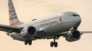 An American Airlines plane landing under a cloudy sky