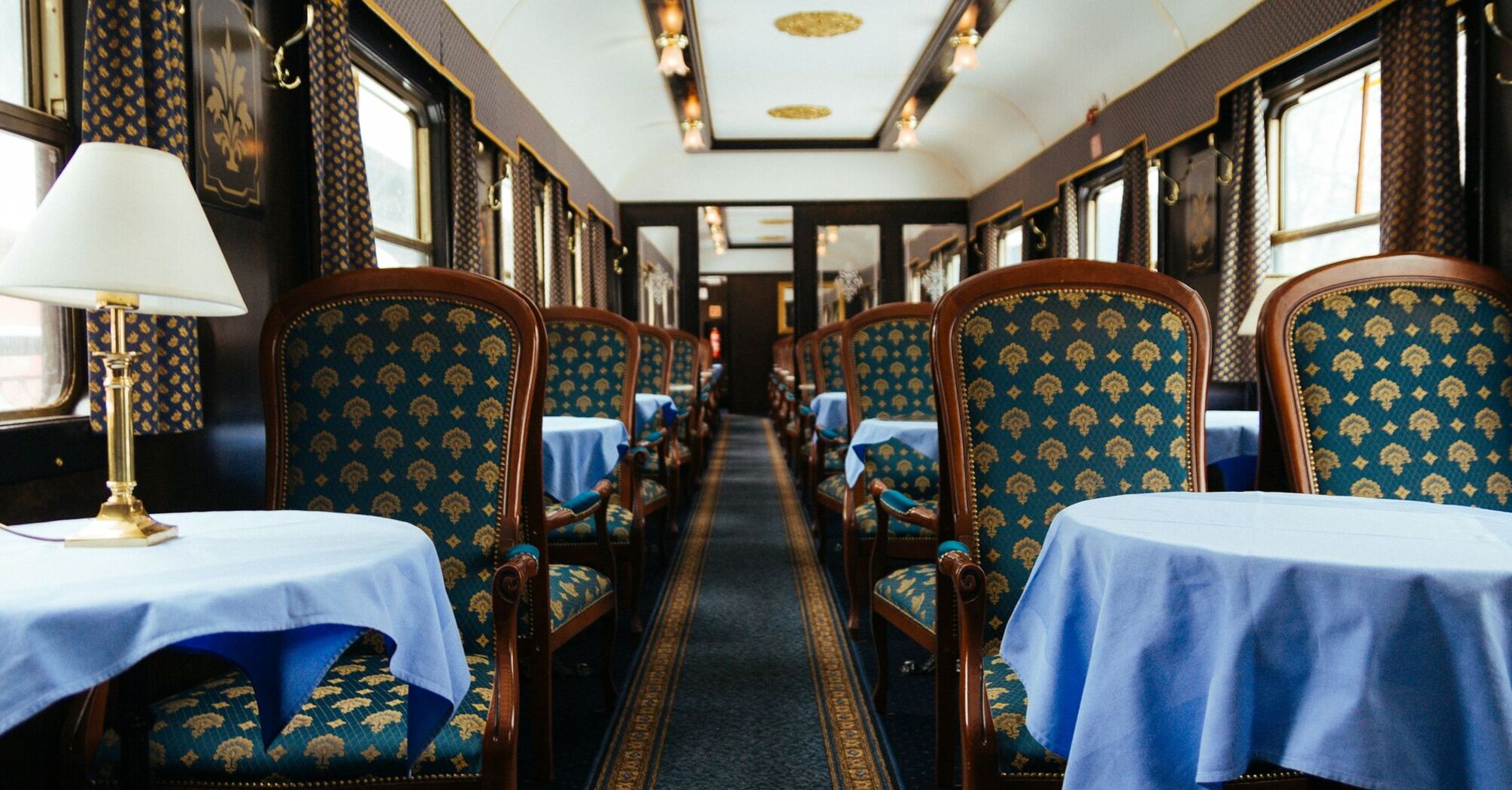 Interior of a luxury train dining car with ornate blue and gold furnishings and elegant tables