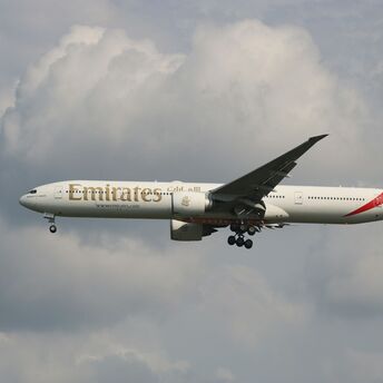 Emirates plane in flight against a cloudy sky