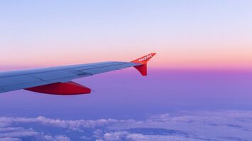 A view of an EasyJet airplane wing with a vibrant sunset sky in the background