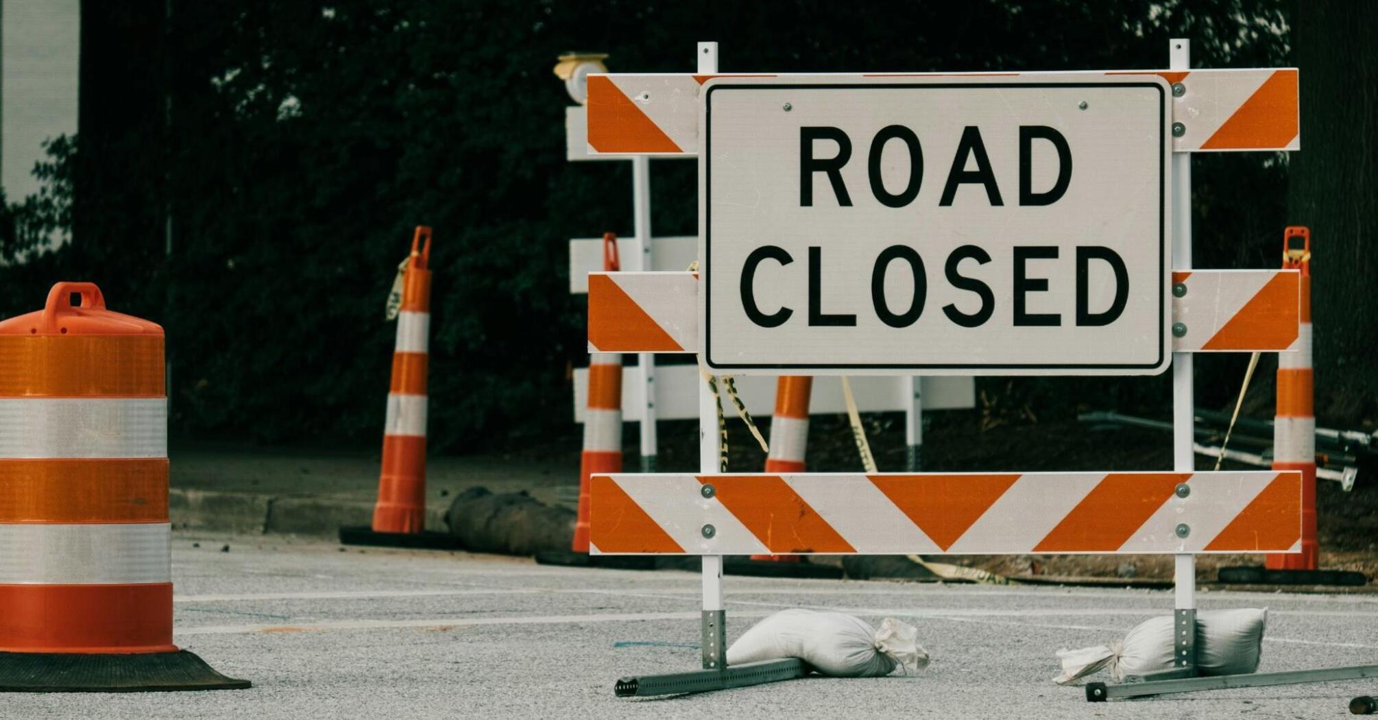 Road closure sign with traffic cones on a blocked roadway