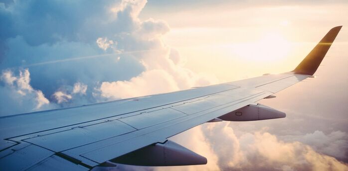 An airplane wing above the clouds during sunrise