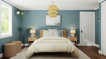 A cozy bedroom with a light beige bedspread, wooden furniture, blue walls, and natural lighting through a window