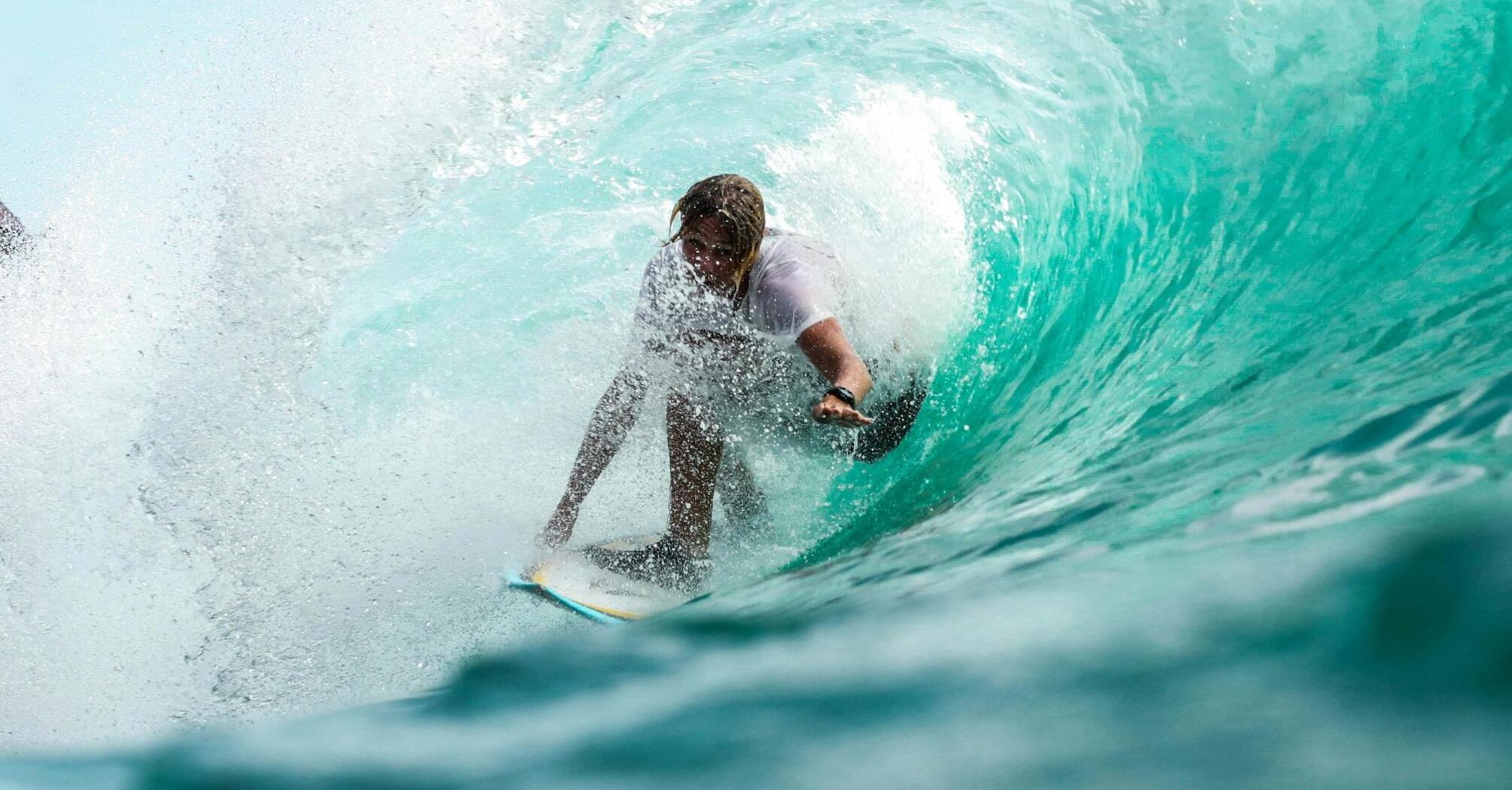 A surfer riding a powerful turquoise wave in a controlled environment