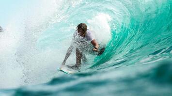 A surfer riding a powerful turquoise wave in a controlled environment