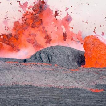 A vivid volcanic eruption with lava spewing and flowing over rugged terrain