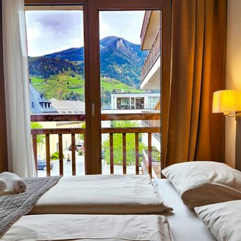 Cozy bedroom with a scenic mountain view through a large wooden-framed window