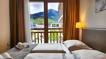 Cozy bedroom with a scenic mountain view through a large wooden-framed window