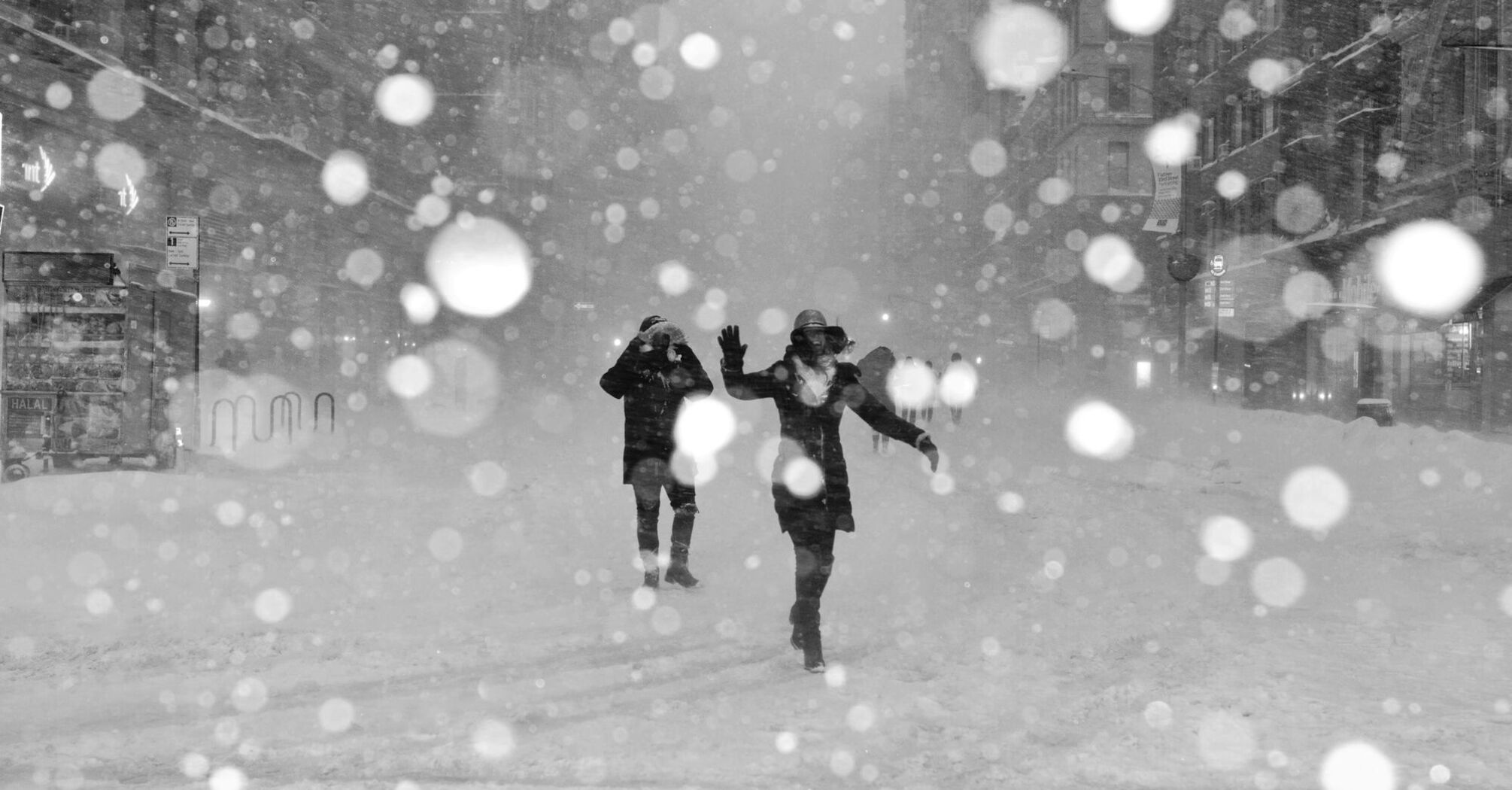 People walking through heavy snowfall in an urban area during a storm