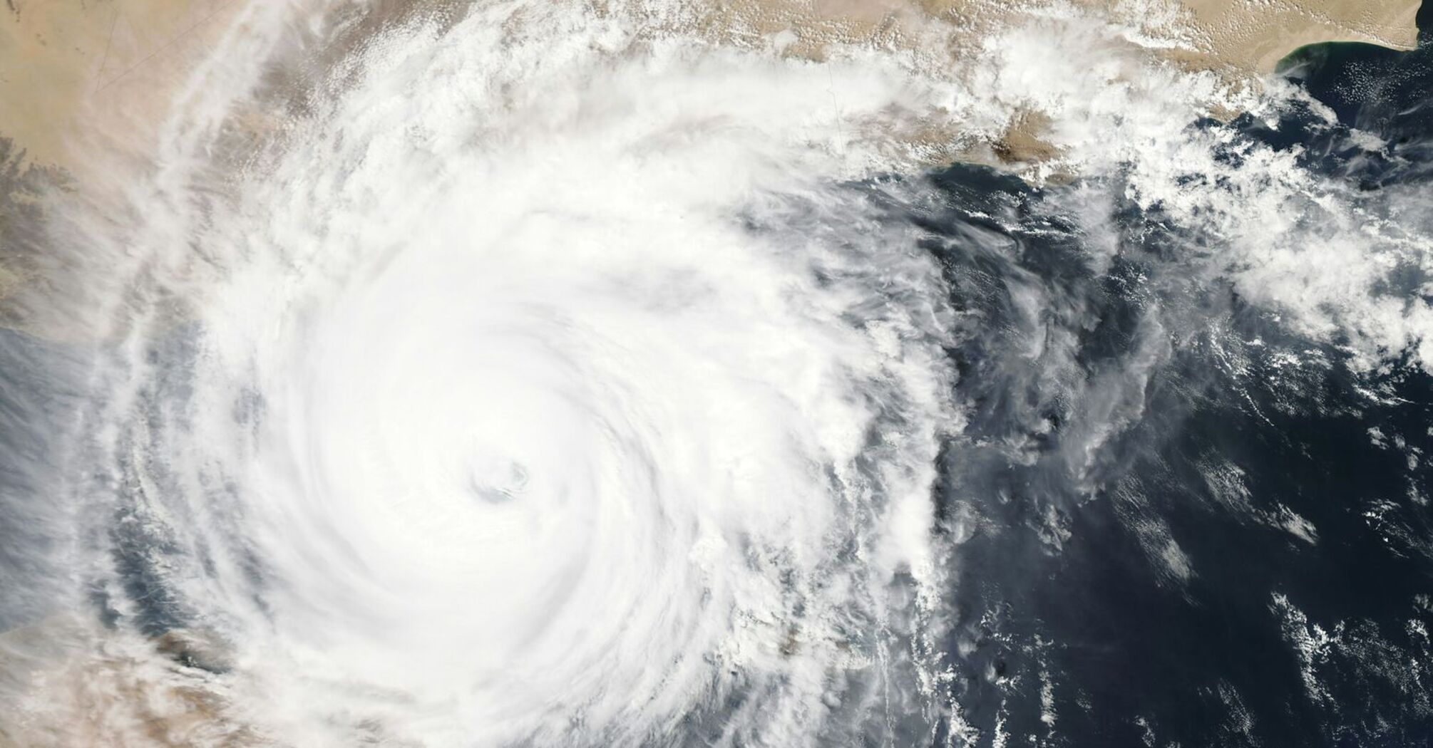 A satellite view of a powerful storm over a coastal region, showcasing its large swirling cloud formations