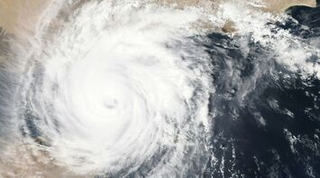 A satellite view of a powerful storm over a coastal region, showcasing its large swirling cloud formations