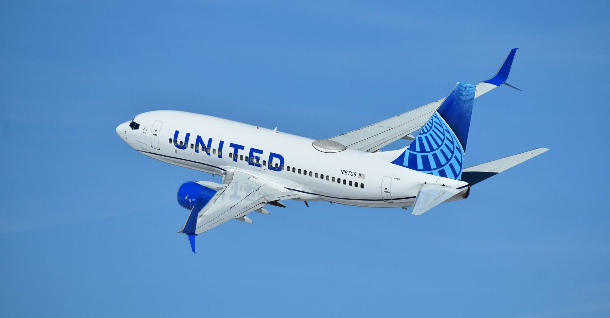 United Airlines airplane flying against a clear blue sky