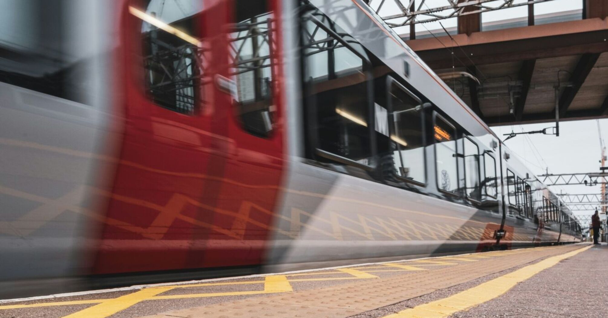 A modern train arriving at a station platform, with directional markings on the ground for passenger guidance