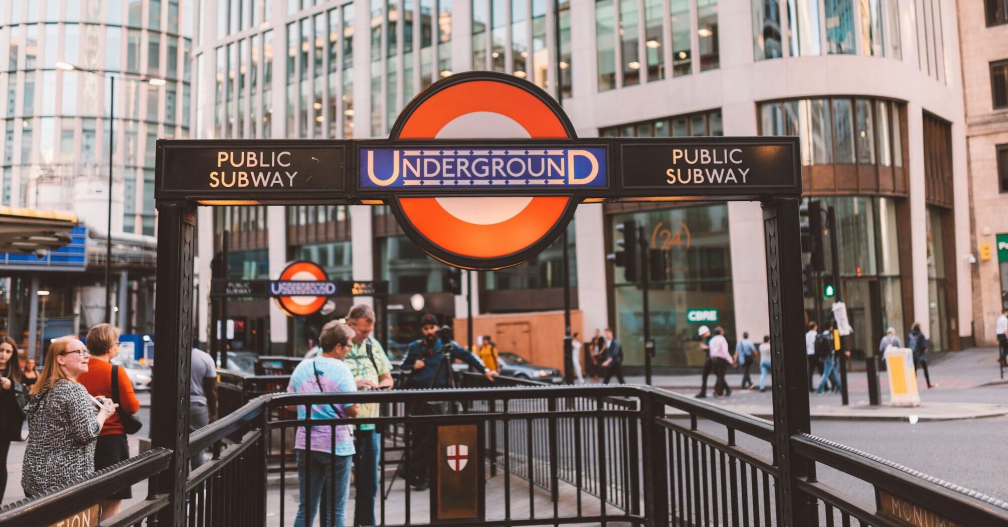 London Underground entrance with people and modern buildings in the background