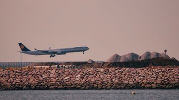 A Lufthansa airplane landing near a rocky coastline under a clear sky