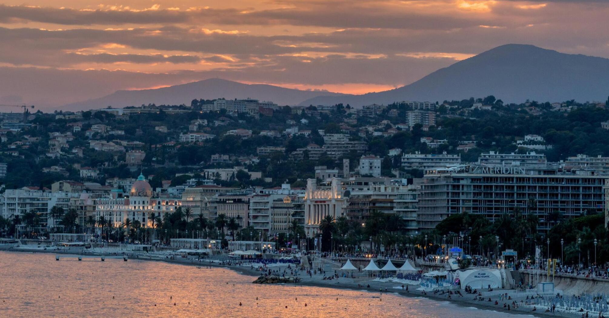 Sunset view of Nice, France, showcasing its coastline, historic buildings, and mountainous backdrop