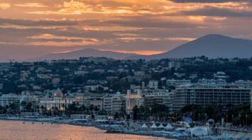 Sunset view of Nice, France, showcasing its coastline, historic buildings, and mountainous backdrop