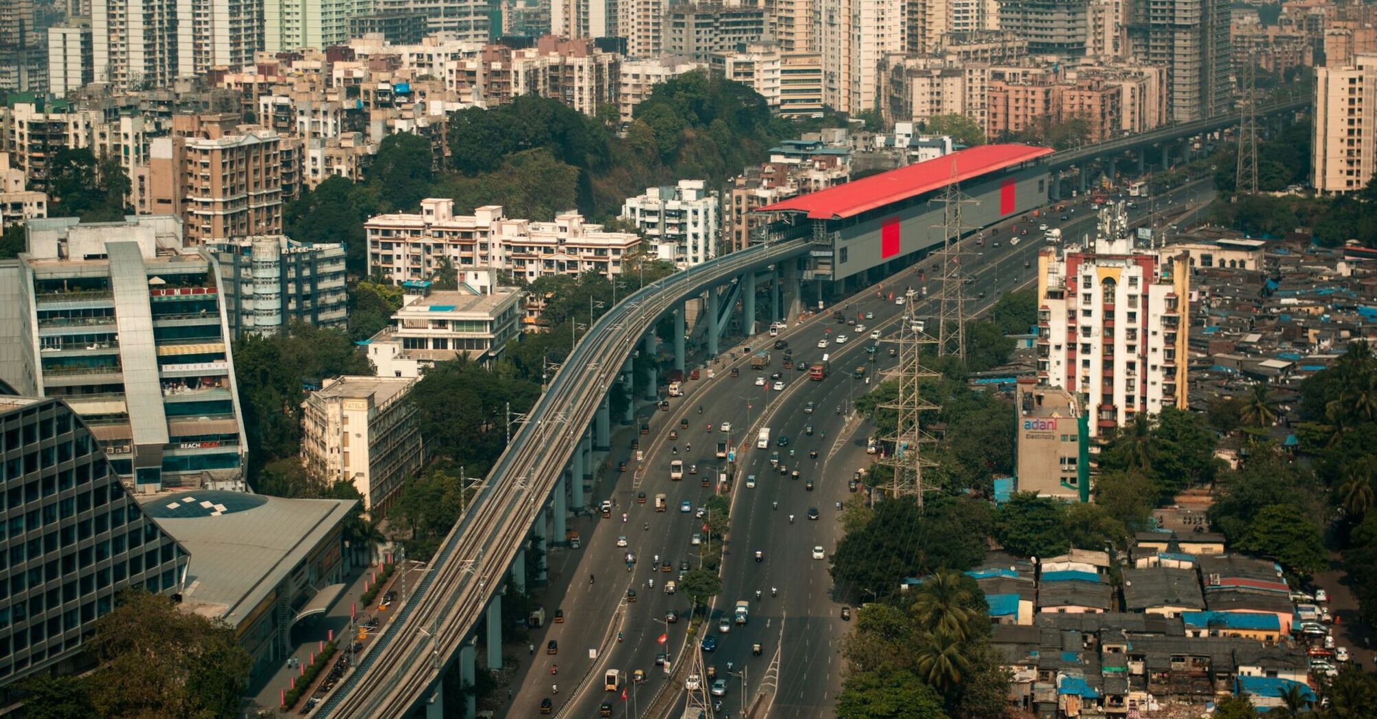 A modern urban landscape with elevated metro tracks, busy roads, and high-rise buildings showcasing urban mobility infrastructure