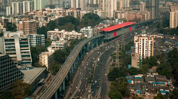 A modern urban landscape with elevated metro tracks, busy roads, and high-rise buildings showcasing urban mobility infrastructure