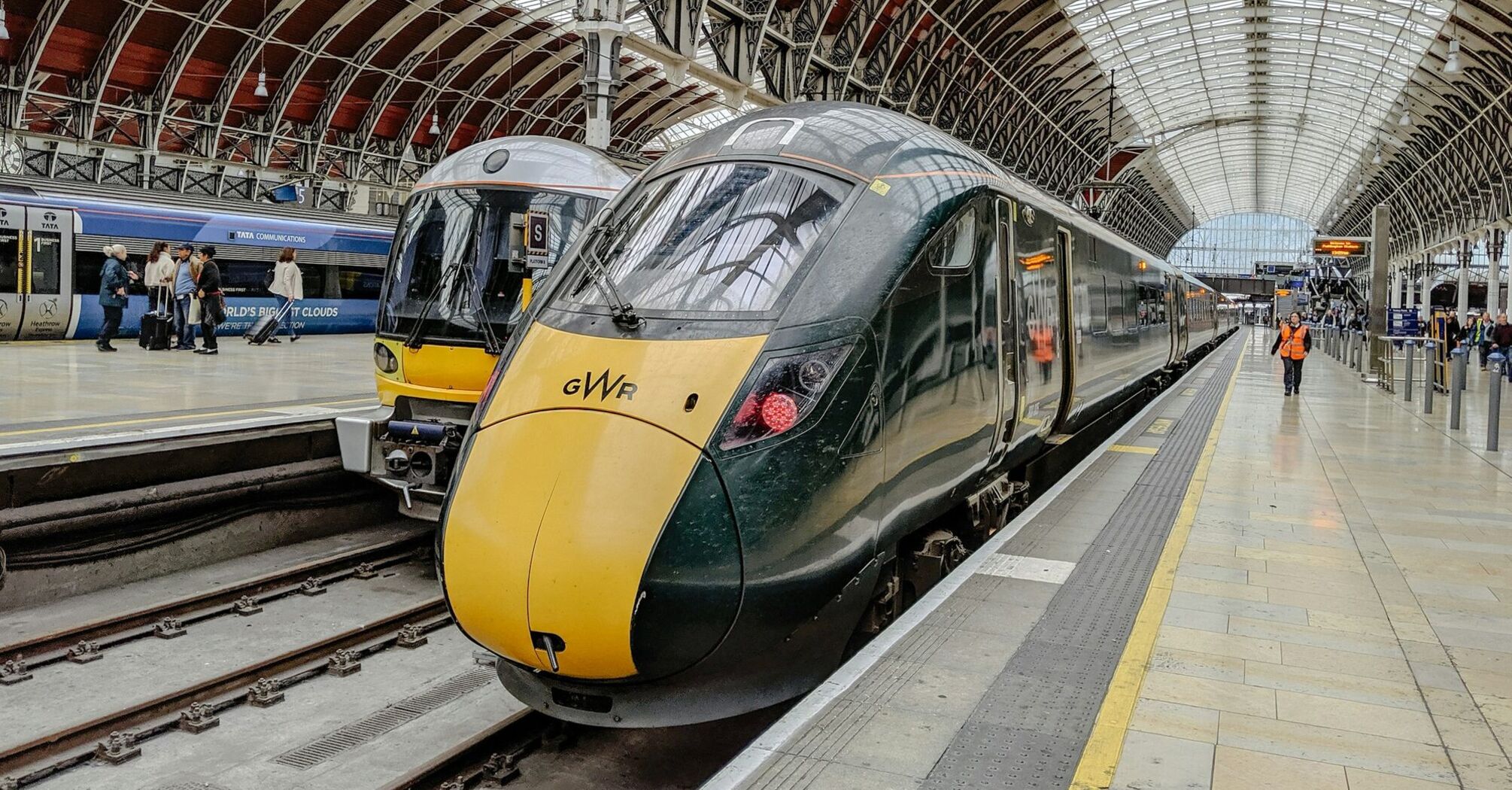 A busy train platform at London Paddington station featuring Great Western Railway trains under a large arched roof