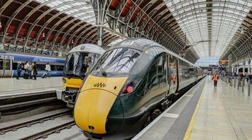 A busy train platform at London Paddington station featuring Great Western Railway trains under a large arched roof