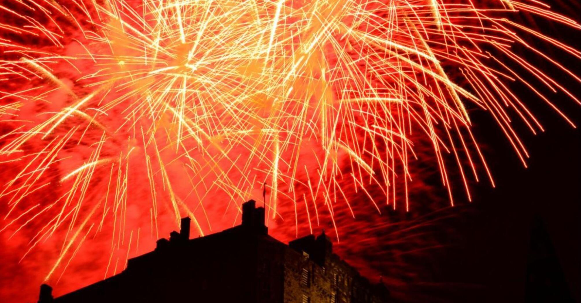 Bright red fireworks illuminating the night sky above Edinburgh Castle