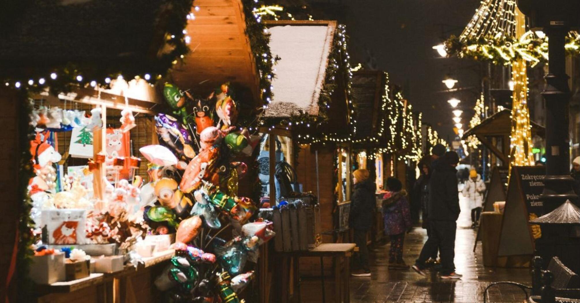 Christmas market stalls with festive lights and decorations on a rainy evening