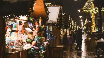 Christmas market stalls with festive lights and decorations on a rainy evening