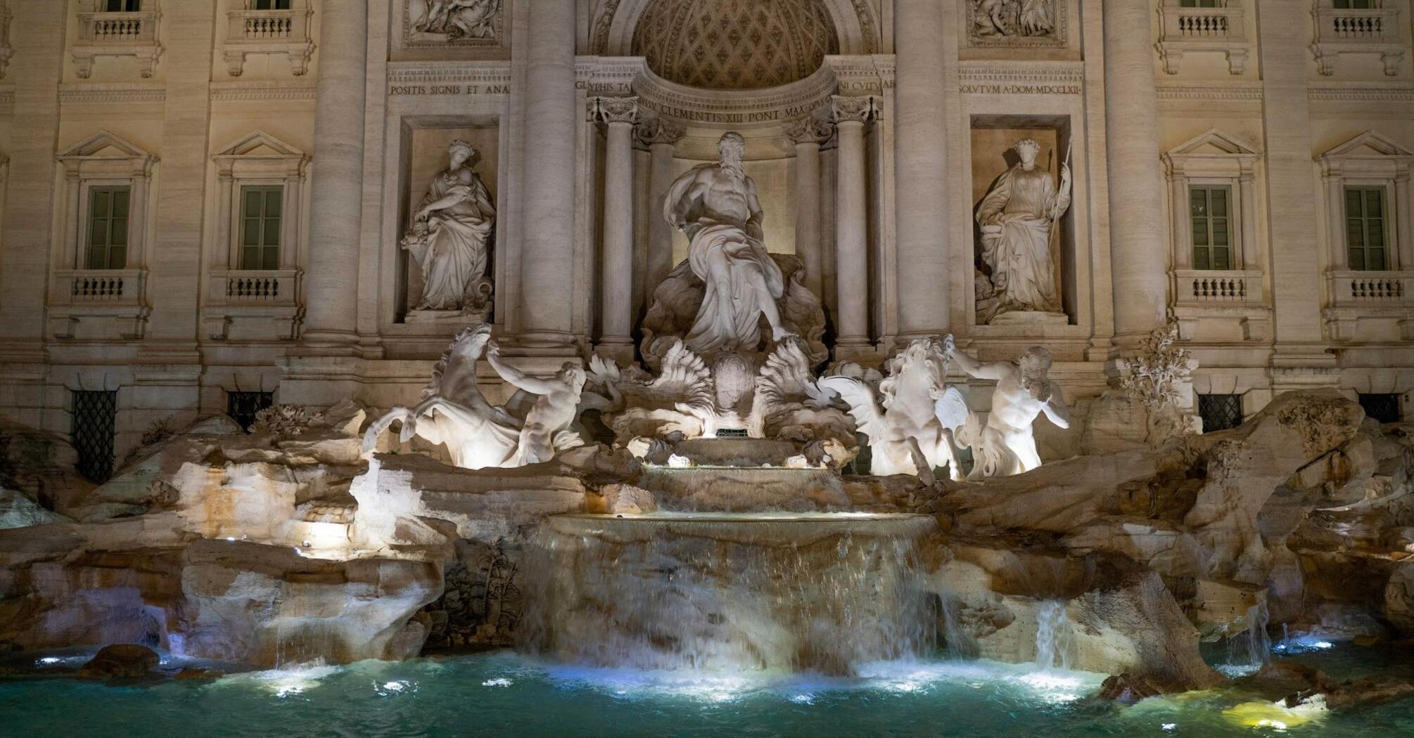 The Trevi Fountain in Rome illuminated at night, showcasing its intricate Baroque sculptures