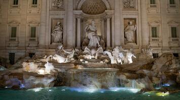 The Trevi Fountain in Rome illuminated at night, showcasing its intricate Baroque sculptures