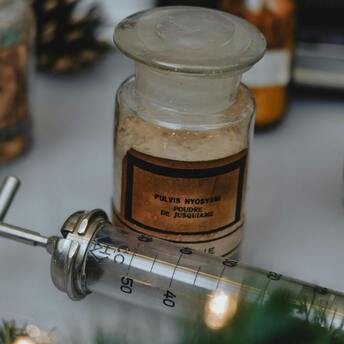 Vintage medical bottle labeled 'Pulvis Hyoscyami' and a metal syringe