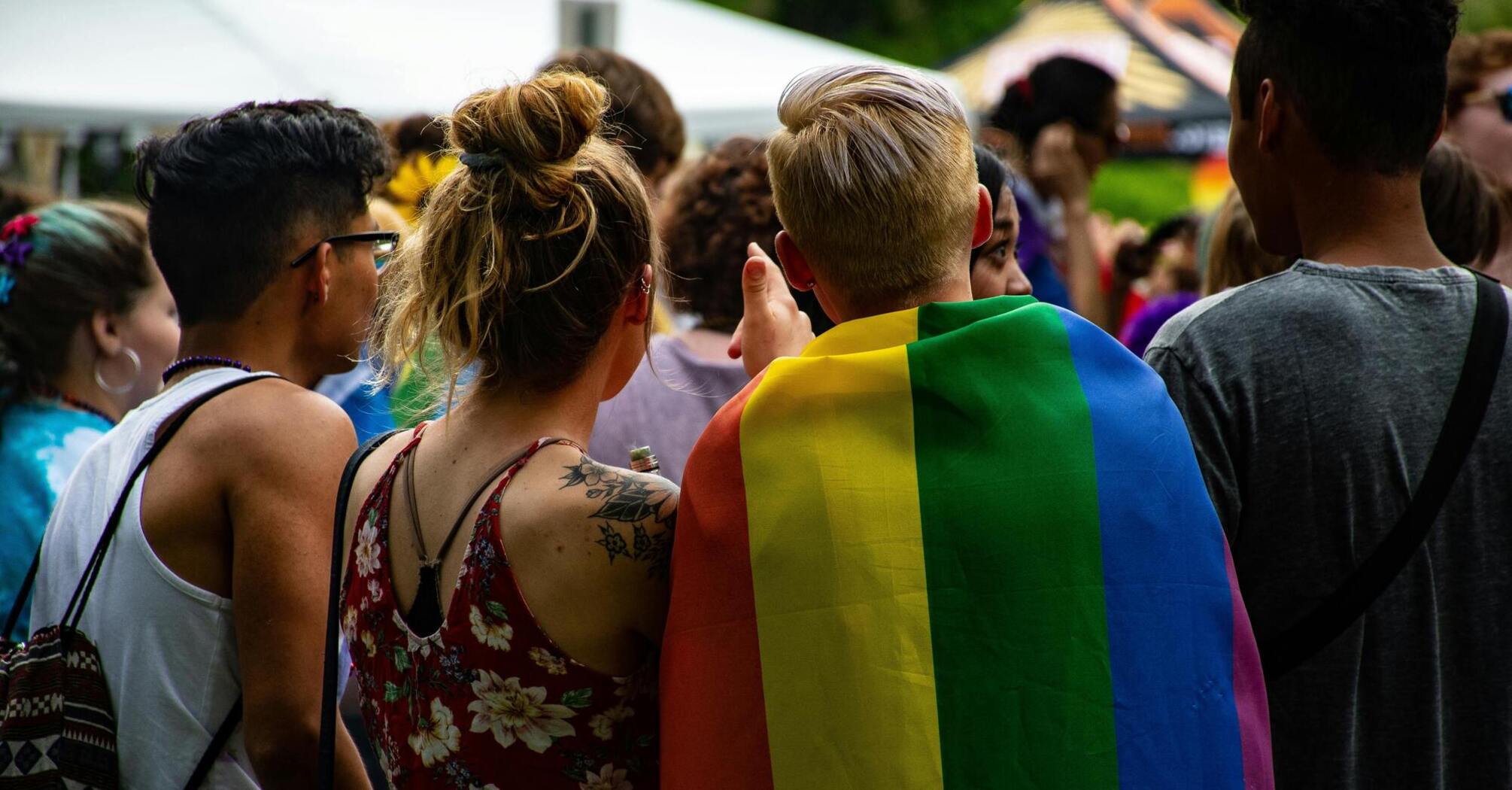 Group of people at an LGBTQ+ pride event with a rainbow flag