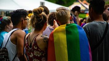 Group of people at an LGBTQ+ pride event with a rainbow flag