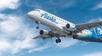 Alaska Airlines plane in flight against a clear blue sky