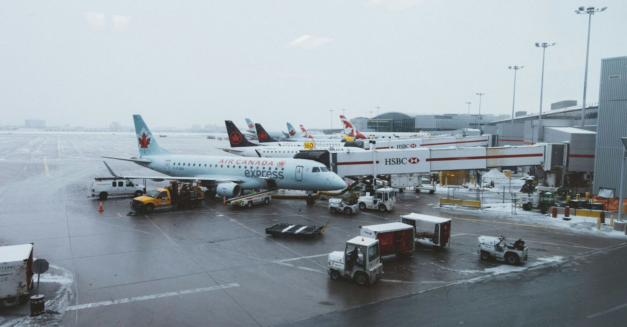 Air Canada planes parked at a snowy airport terminal with ground support vehicles in operation