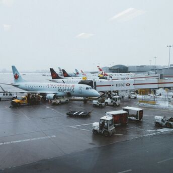 Air Canada planes parked at a snowy airport terminal with ground support vehicles in operation