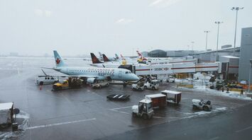 Air Canada planes parked at a snowy airport terminal with ground support vehicles in operation