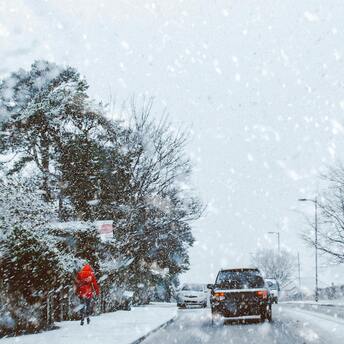 Snow-covered street with cars and pedestrians during heavy snowfall