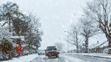 Snow-covered street with cars and pedestrians during heavy snowfall