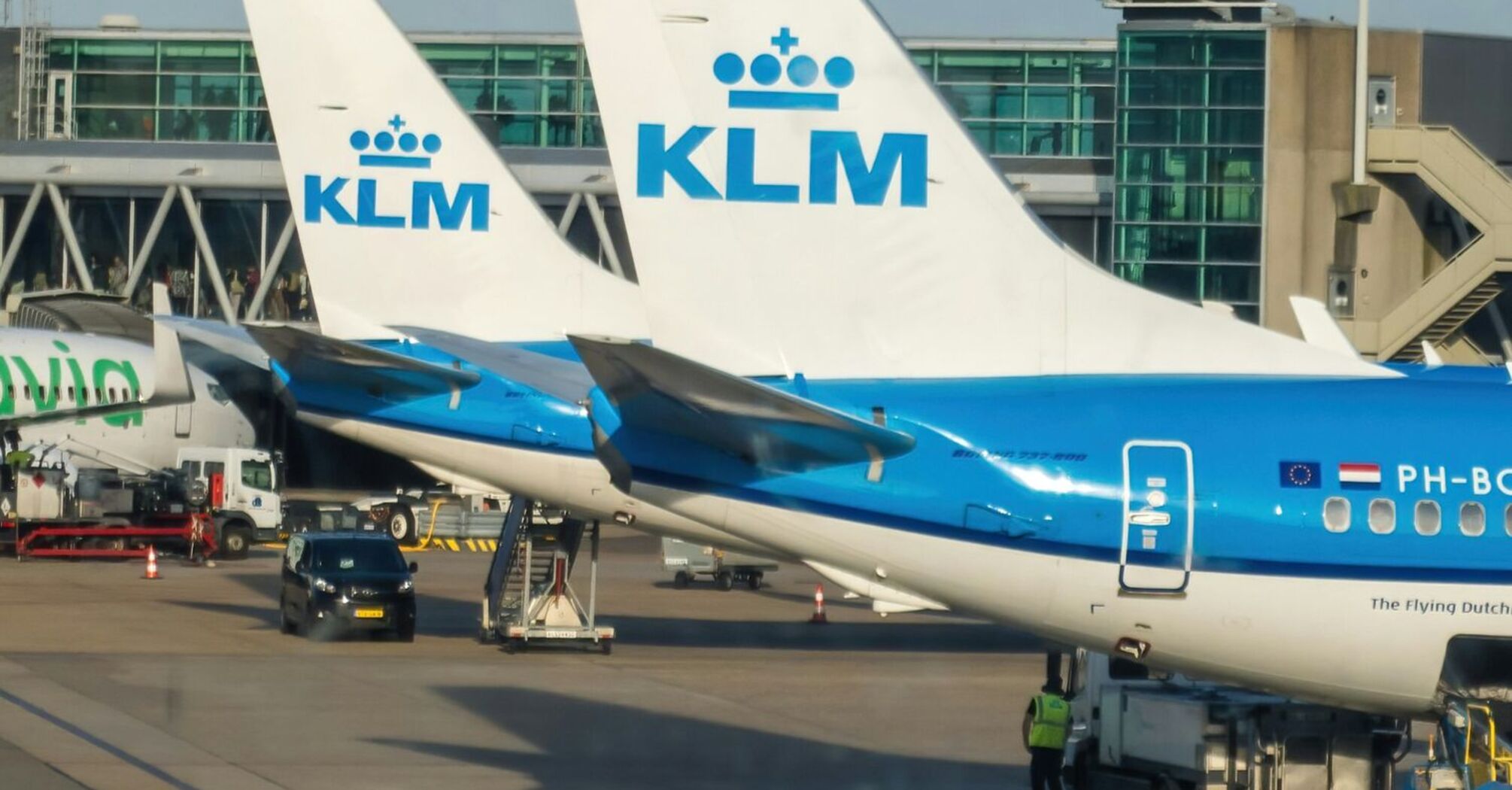 KLM aircraft parked at Amsterdam Airport Schiphol with visible ground services operating nearby