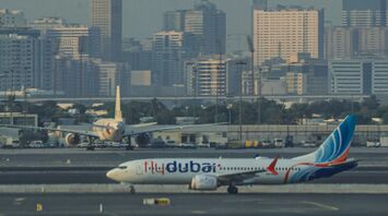 A flydubai aircraft taxiing on the runway with a city skyline in the background