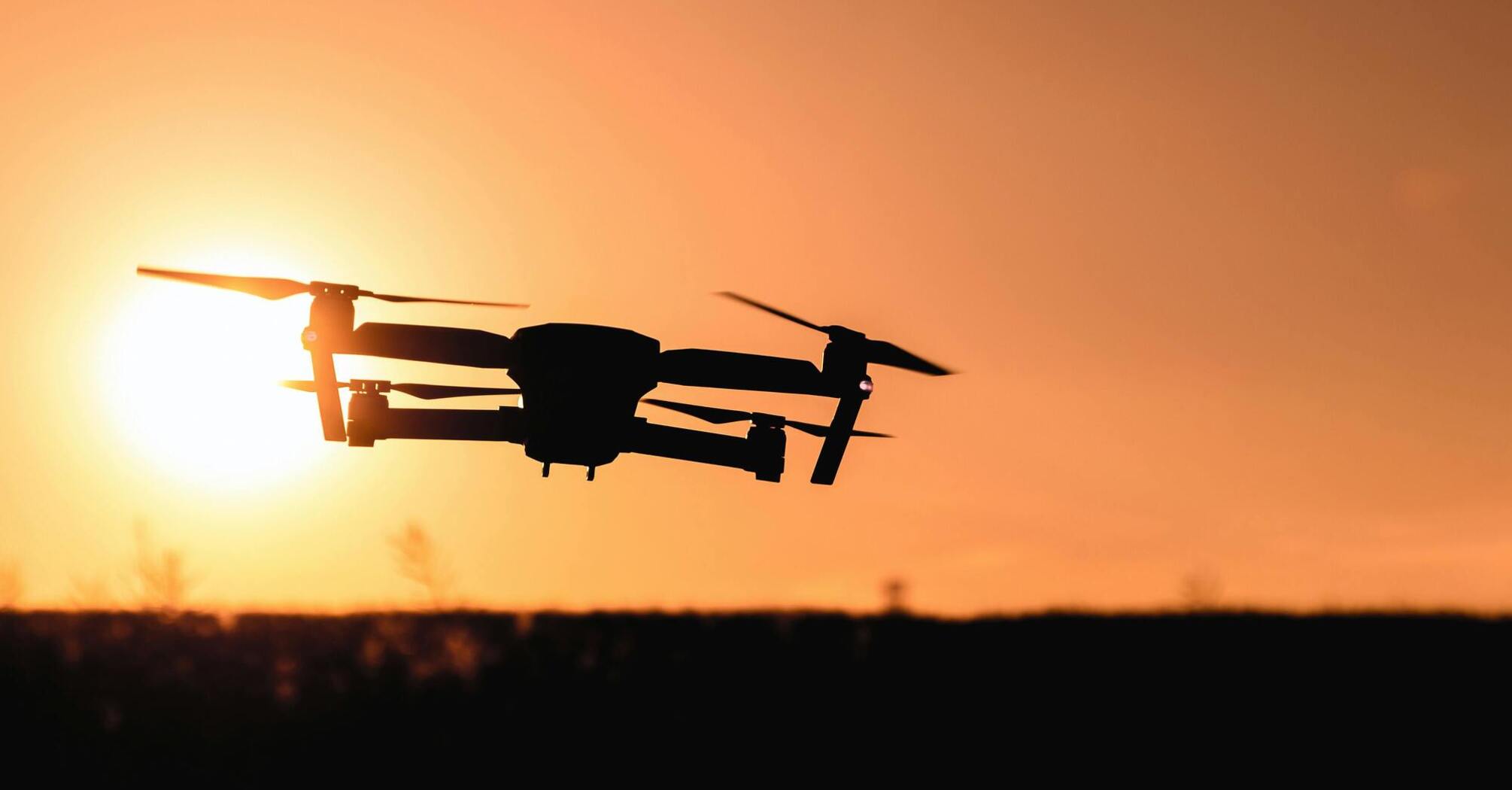 Drone silhouetted against a sunset sky